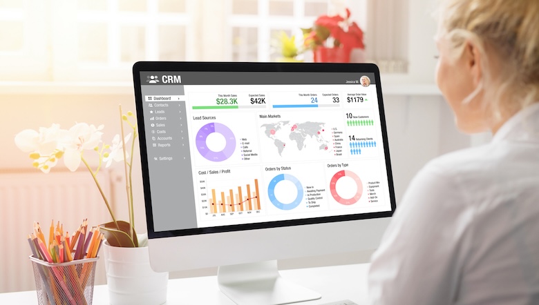 A woman looking at a CRM dashboard on a computer screen.